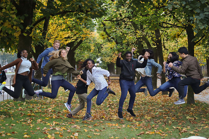 Eine Gruppe von internationalen Student*innen springt in die Luft