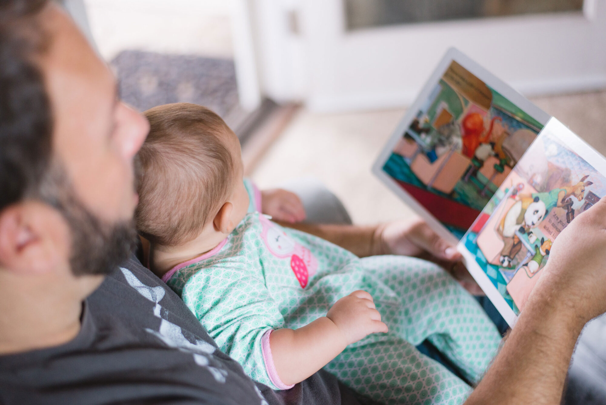Junger Vater liest Buch mit Baby